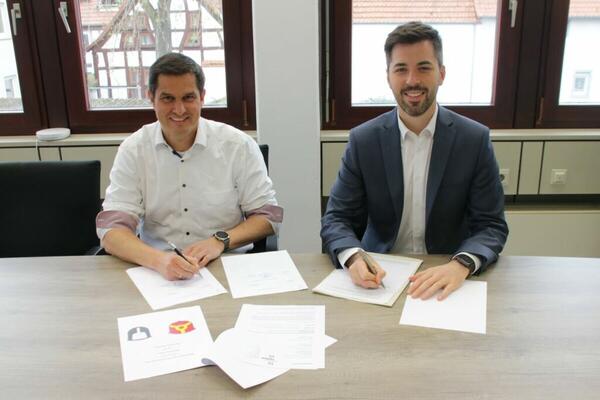 Nauheims Bürgermeister Jan Fischer (links) und Treburs Bürgermeister Jochen Engel (rechts) unterzeichnen eine Vereinbarung zur Interkommunalen Zusammenarbeit im Bereich Digitalisierung
